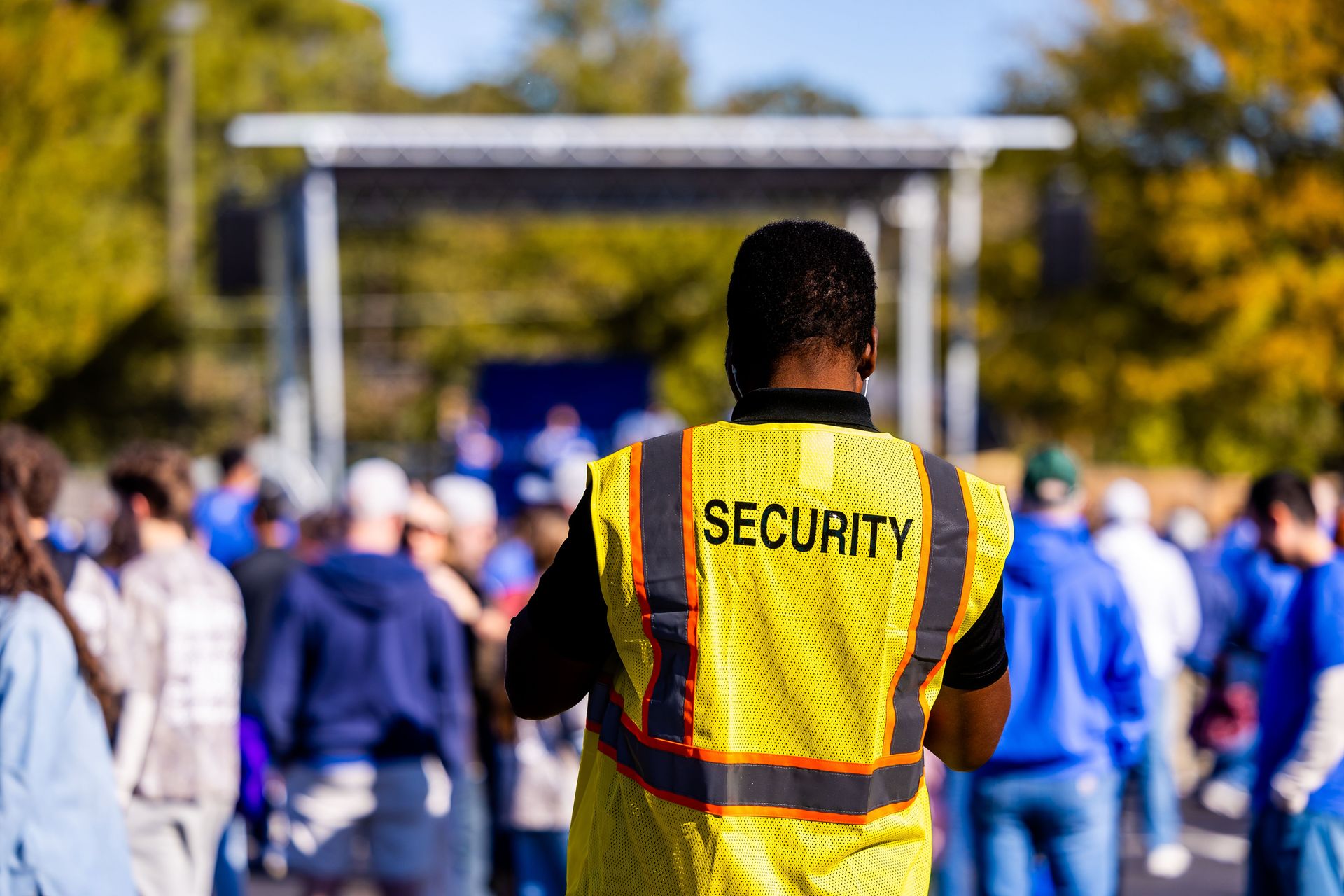 A security guard monitors a crowd at an outdoor event, ensuring safety and order.